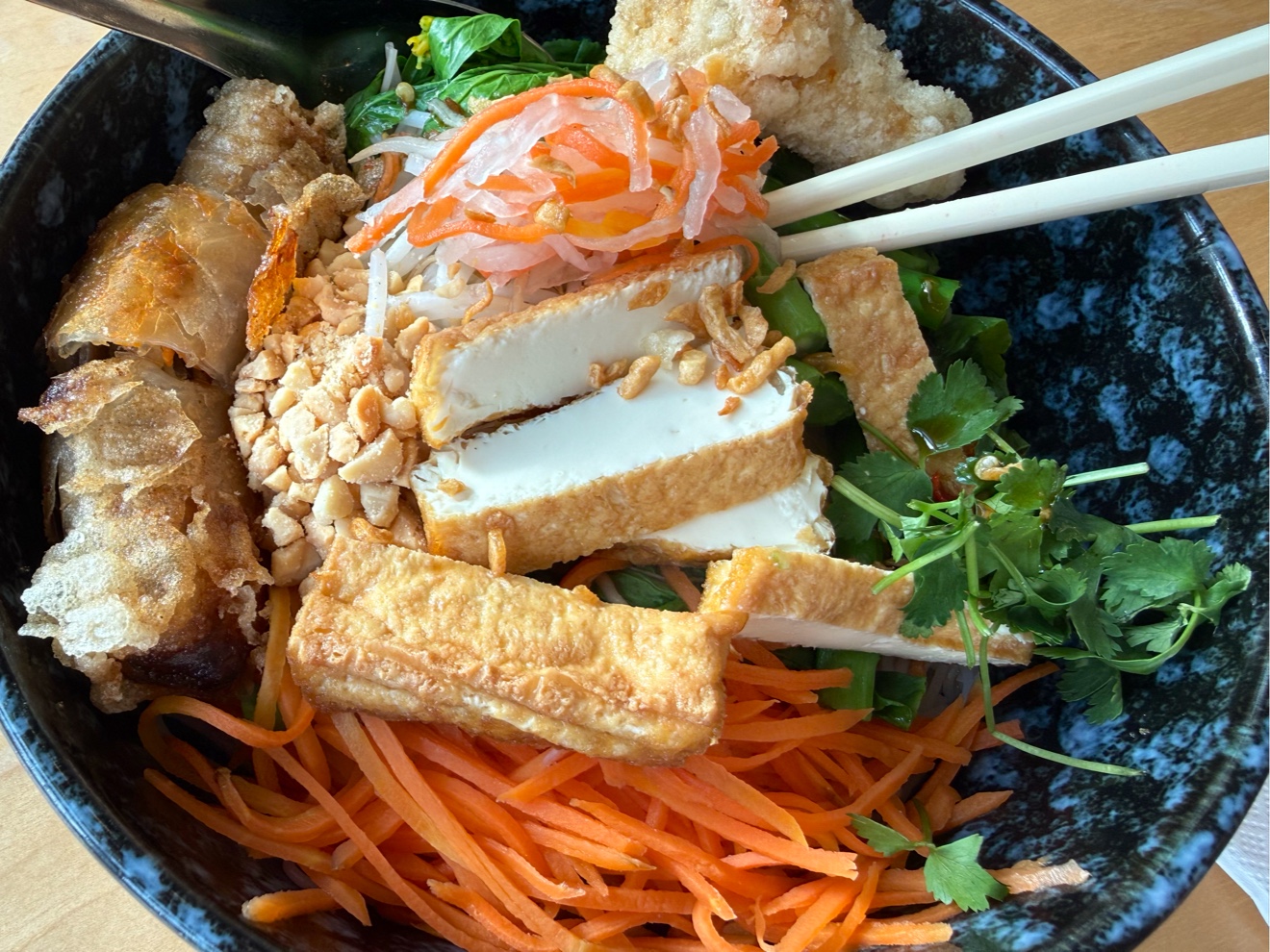 Vermicelli bowl with crispy tofu, vegetables and spring rolls